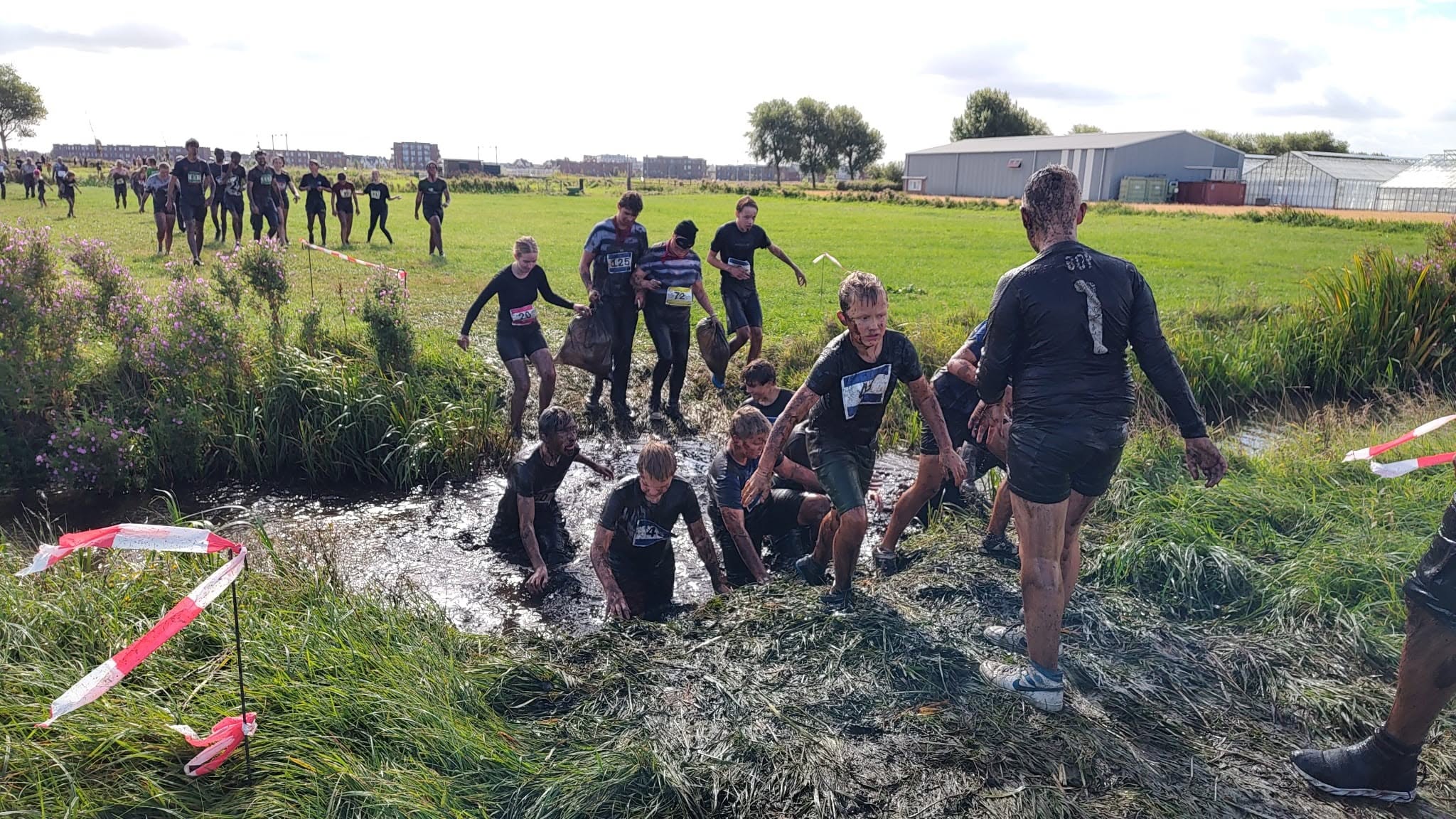 Deelnemers door de bagger tijdens de Baggerloop