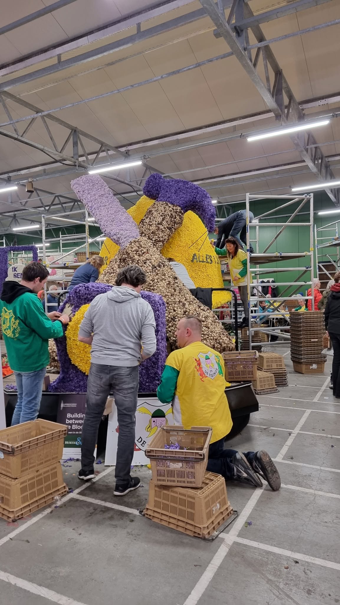 Leden helpen bij het bloemen steken voor het Bloemencorso